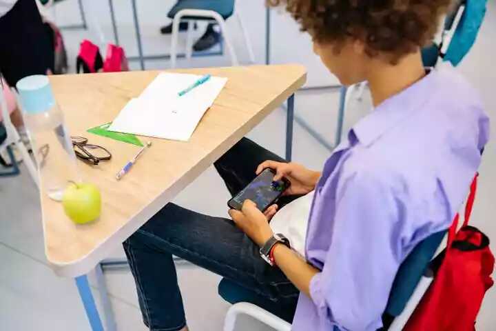 Adolescent qui joue avec son téléphone pendant un cours à l'école
