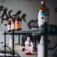Des bouteilles avec des substances chimiques sur une étagère dans un milieu qui semble insalubre.